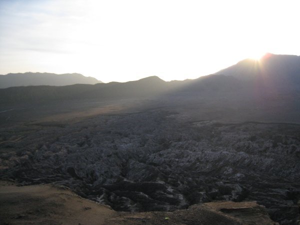 The sun breaking the horizon over the crater wall.