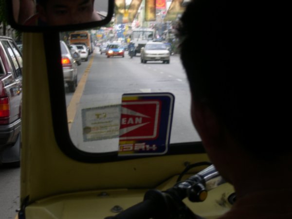 Out tuk tuk driver on the wrong side of the road being flashed by an oncoming car