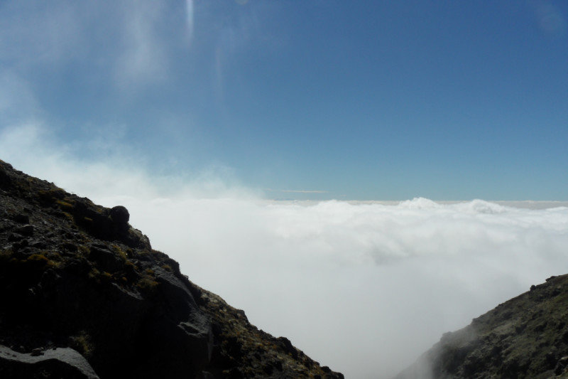 De wolken belemmeren het uitzicht naar beneden maar in de verte kunnen we wel de bergen in het Tongariro national park zien liggen