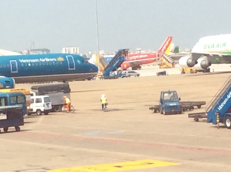 Two people randomly cycling around on the Tarmac between taxiing planes