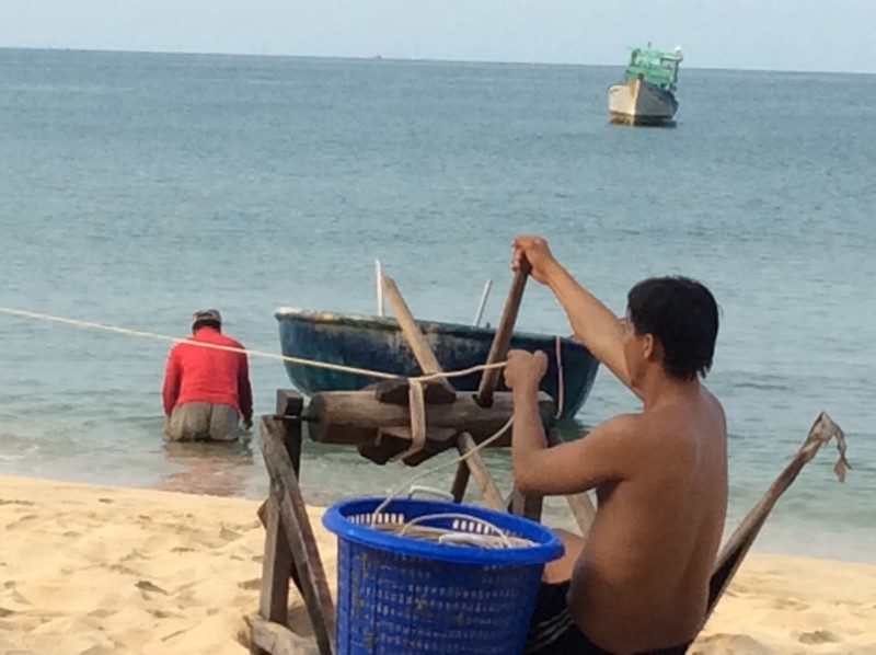 Motorised bucket behind, washing his catch in the sea