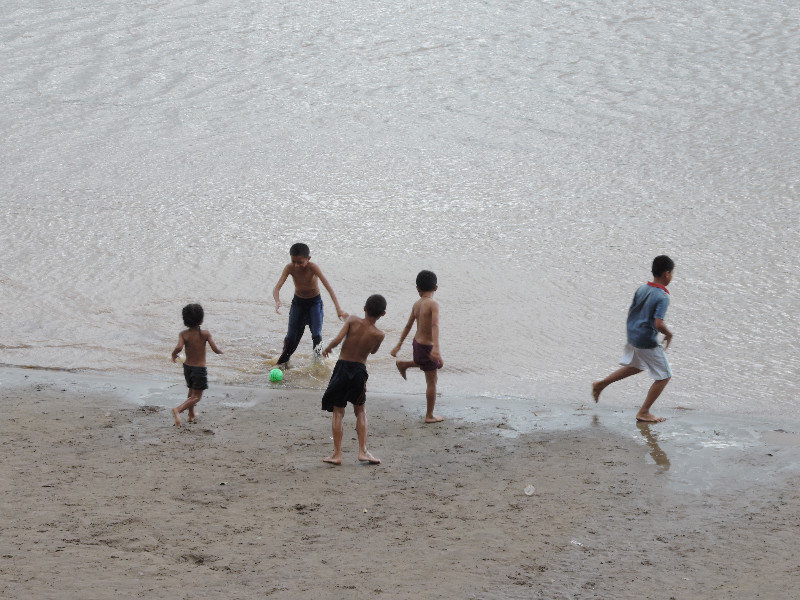 Kinder spielen Fussball am Strand