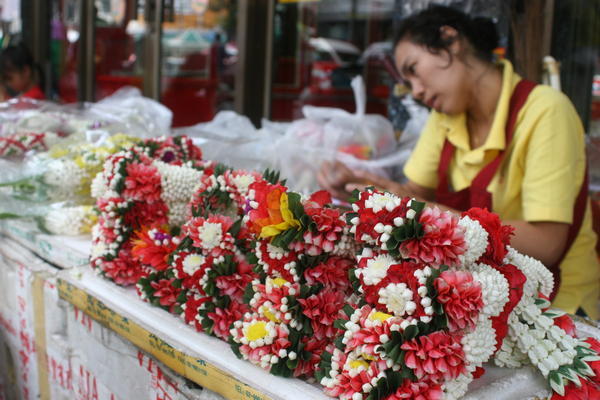 Lady talking on her cell phone while making offering flowers