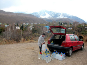 Kyrgyz lady getting lots of water at a mountain spring