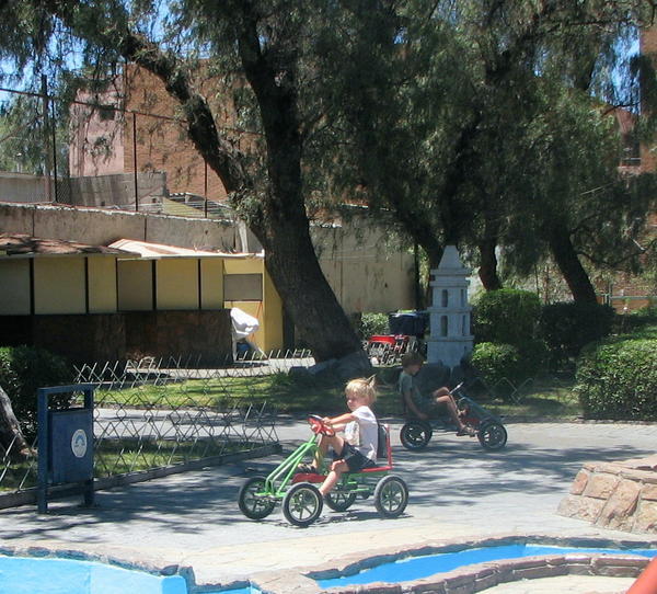 Ben and Oliver riding "bikes" at a park in Calama