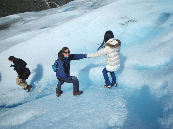 Guide helps a walker on the Perito Moreno Glacier walk