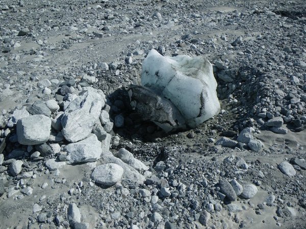 White ice berg with boulders on upstream side.