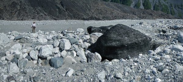 Dark ice berg with boulders on upstream side
