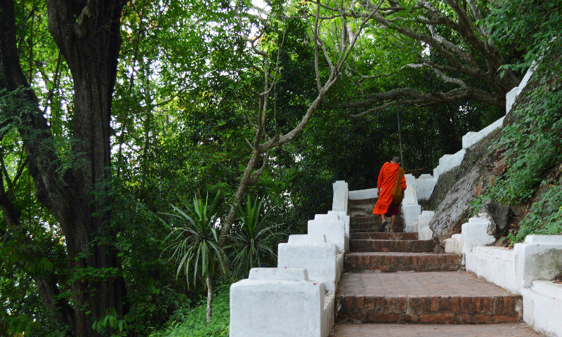 Monk climbing Mount Phou Si to Wat Cham Si
