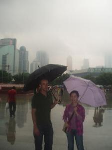 Joe and Fay in the rain surrounded by big buildings