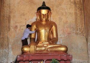 Applying gold leaf to Buddha