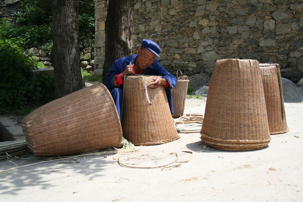Old man hard at work weaving baskets