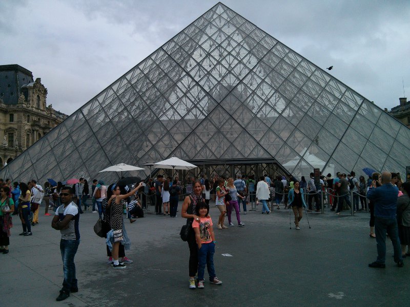 In front of the famous glass pyramid entrance at The Louvre.