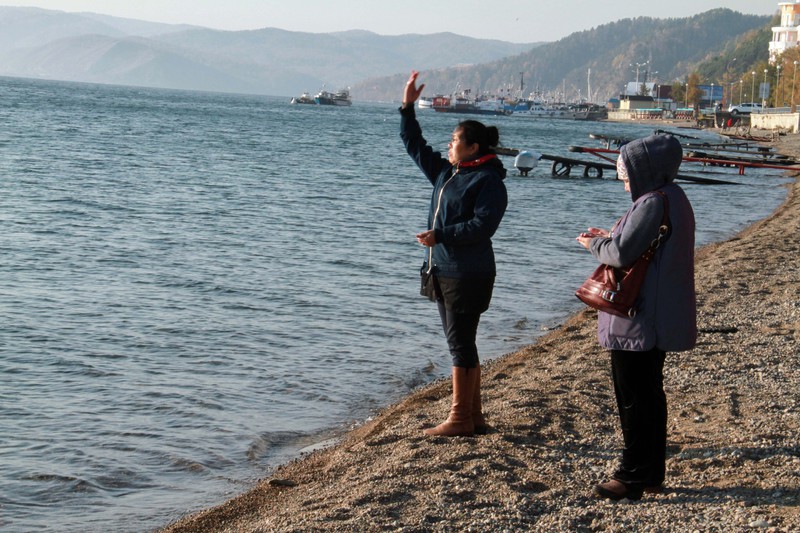 Buryat women throwing pebbles into Lake Baikal