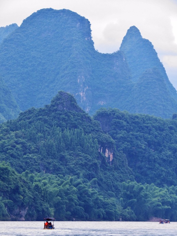 Mountains dwarfing bamboo raft