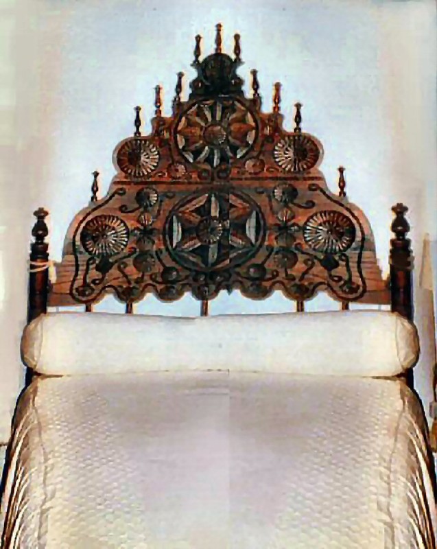 relatively small monk's bed with hand-carved and inlaid headboard