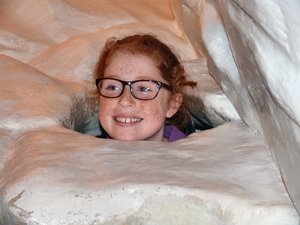 little girl emerging from the top of an ''igloo'' she helped build