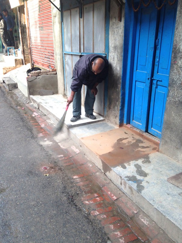 man sweeping in front of his shop