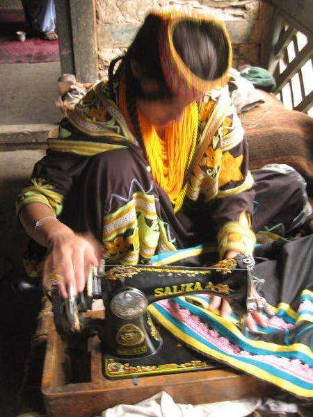 young Kalasha woman sewing a black dress