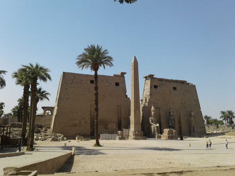 Pylons, colossi, obelisk remains amidst date palms at Luxor temple today 
