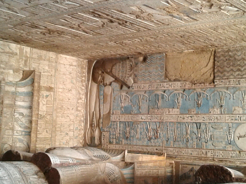 High overhead, neck craning is required to see the corner of the stone ceiling, on the left, a female face and arms outstretched in protection
