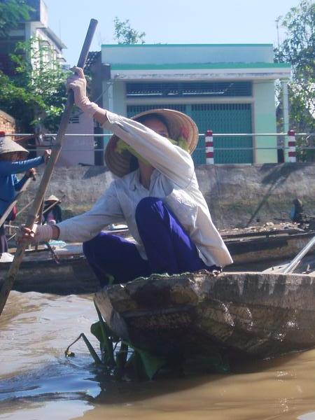 Vietnamese woman rowing through a floating market