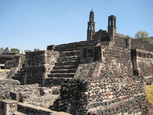 Layers of history: part of an Aztec building with Spanish church behind