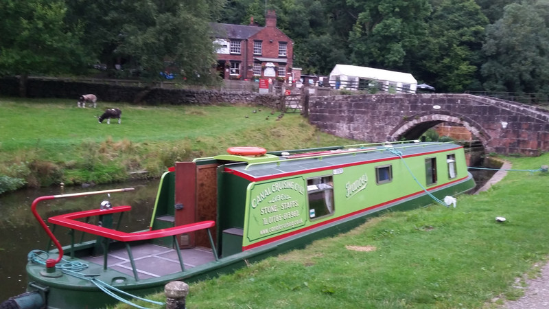 A narrow boat with the Black Lion pub in the distance.