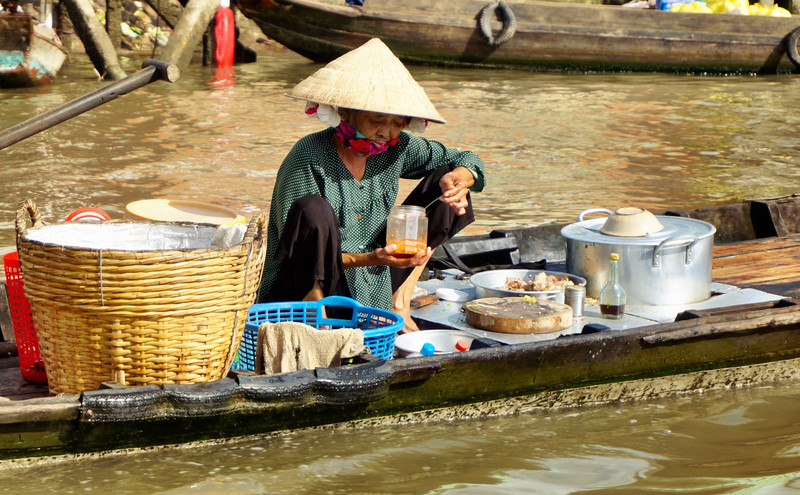 A lady preparing food for sale in the floating market