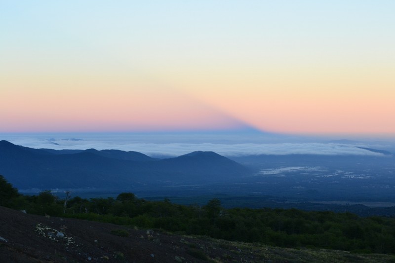 Sunrise casts a shadow of the volcano over the valley