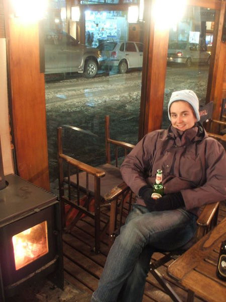 Kirsty drinking beer and warming up near the fire in El Calafate