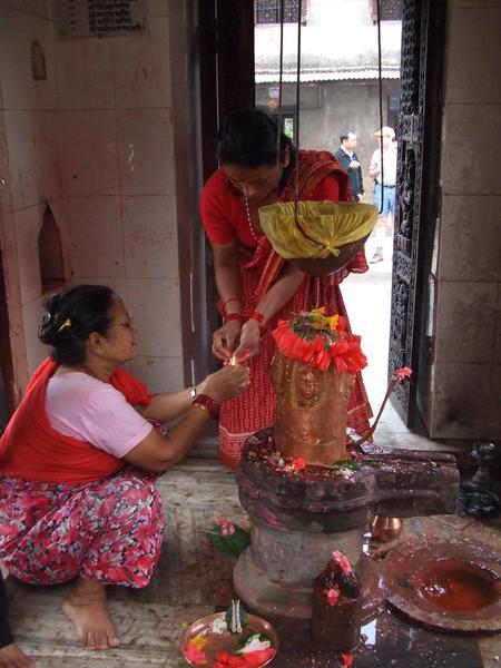 Hindu women decorating shrine for pujas (prayers)