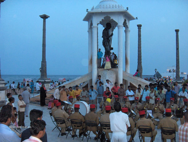 A police band playing in front of the Gandhi statue