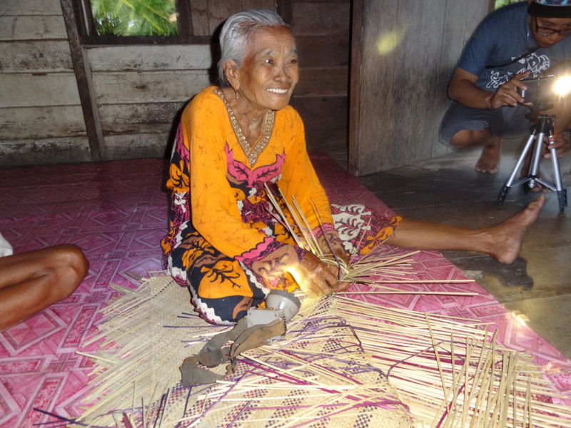 A lady knitting a mat 
