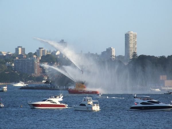 Tugboat Ted Noffs heads across the harbour spraying harbour water as part of the NYE festivities