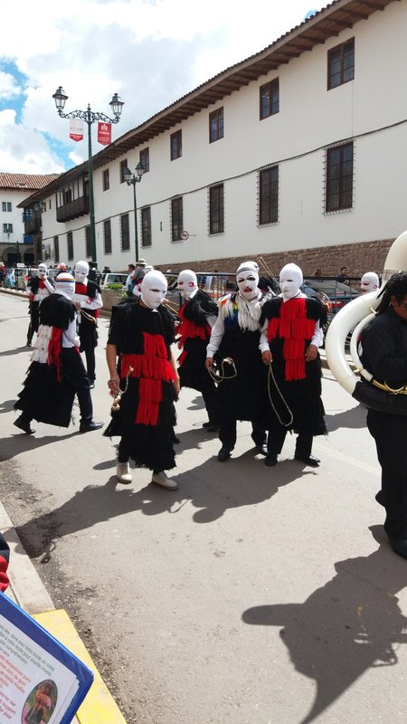 Boys in the procession with covered faces and whips