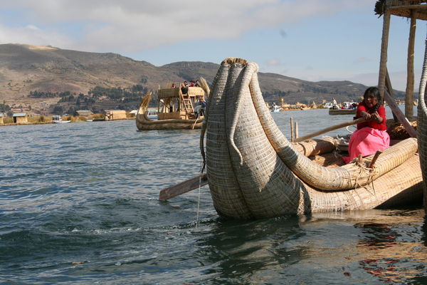 Kinder paddeln Touristenstrohschiffe ueber den Titicacasee