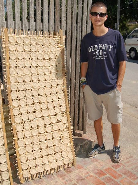 Nick beside rice cakes drying in the sun