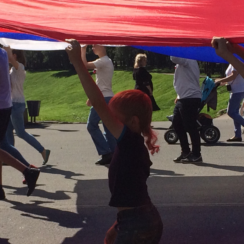 Kids walking with huge national flag.