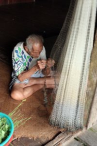 Old man fixing nets at the long house