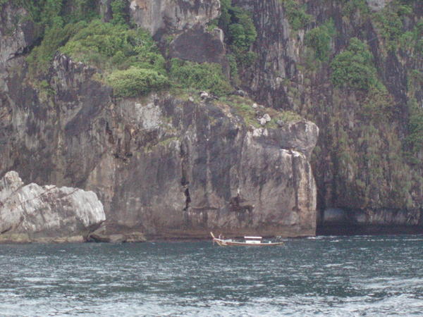 longtail boat in front of cliffs