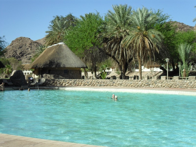 The spa pool surrounded by hills and thatched buildings