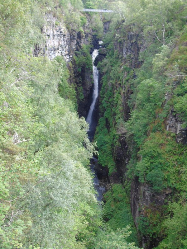 A Victorian suspension bridge spans the gorge above the Falls of Measach which tumble into it