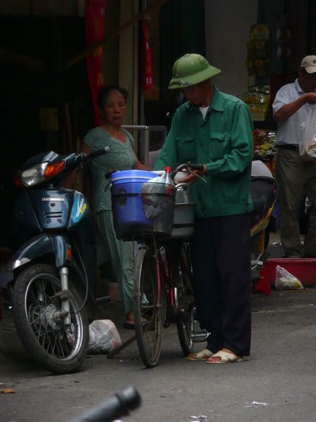 Man in traditional Hanoi hat selling bicycle food