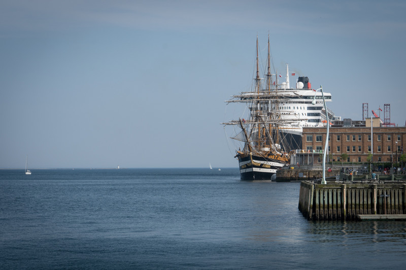 A tall ship overshadowed by a passenger liner in Halifax Harbour