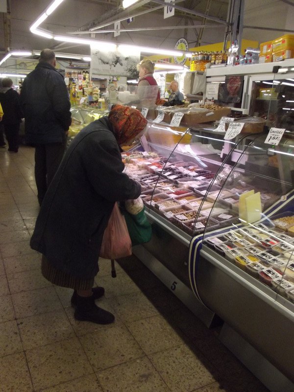 A small, older lady buying goods at the market