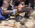 Young boys make fire from sandpaper wood