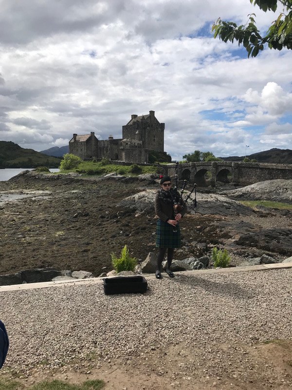 Young female bagpiper with Eileen Donan Castle in the background