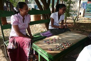 Young girls playing chess with bottle caps.