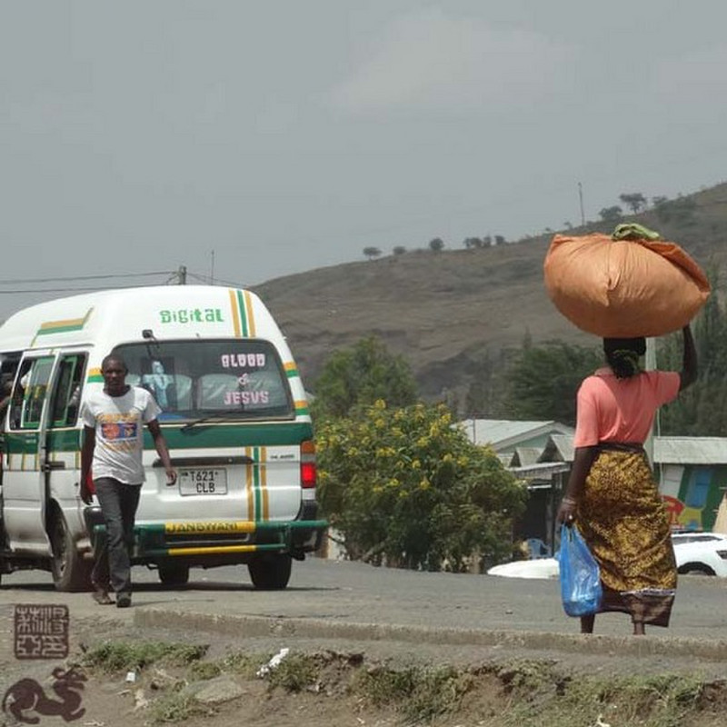 Tanzania-Arusha-Road- Lady caring orange bag